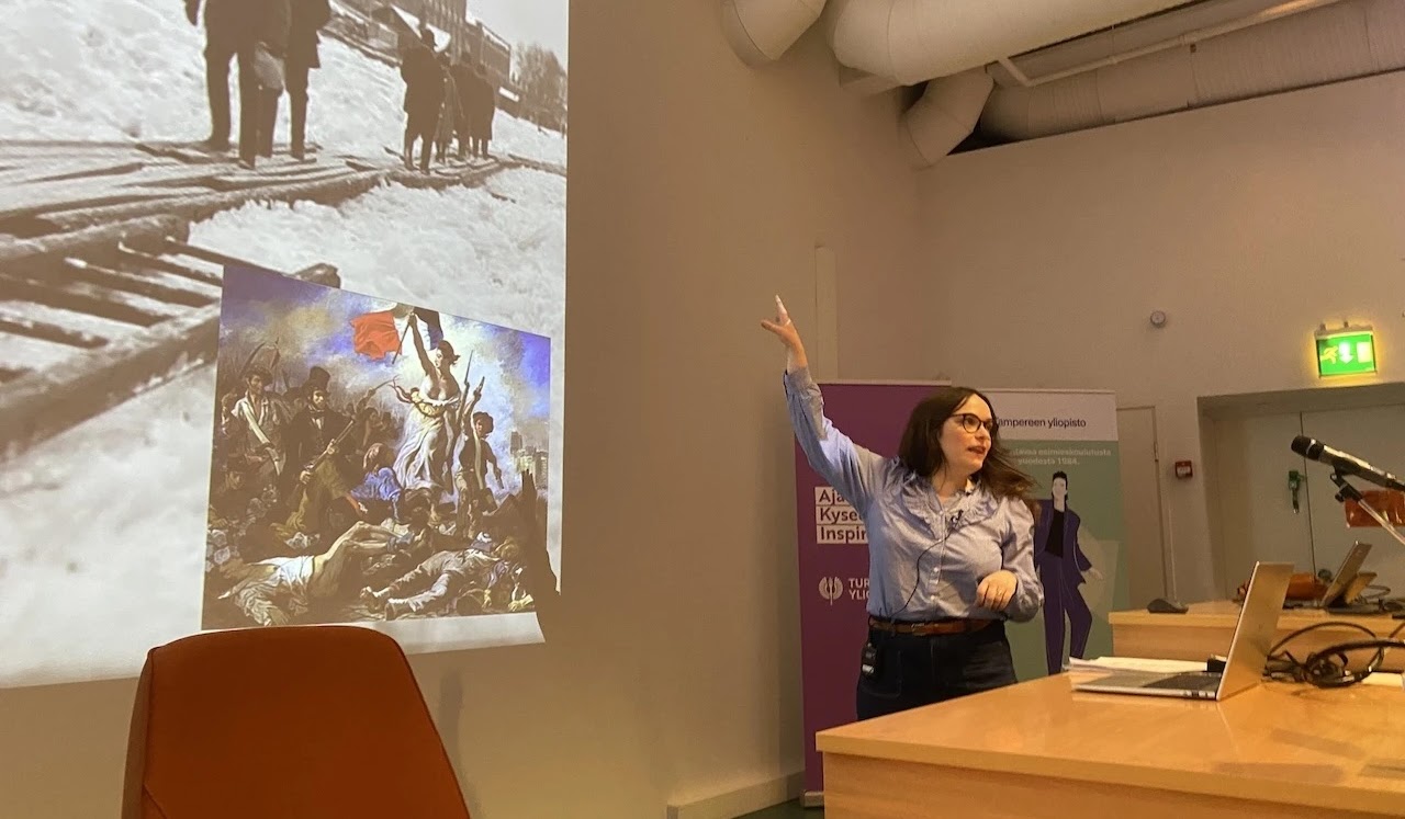 Sanna Kuusikari kertoo kuvasta, jossa jäässä olevan Kokemäenjoen yli vie lautakäytävä. Kuvassa taustalla näkyvä rakennus on puuvillatehdas, nykyinen yliopistokeskus.